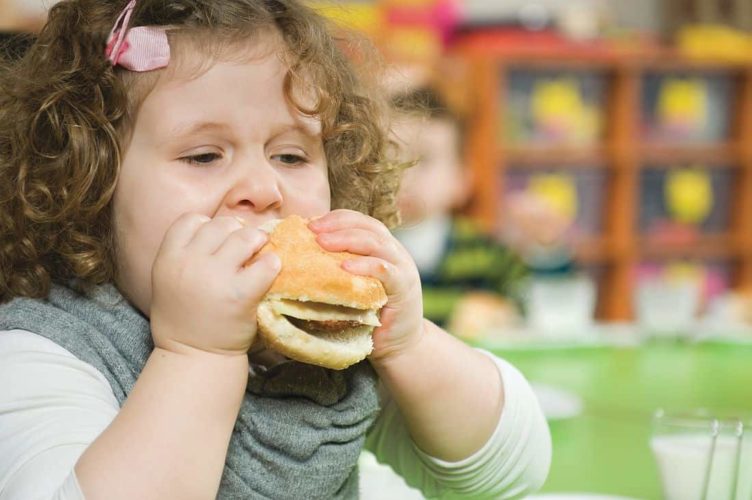 Bambina sovrappeso mangia hamburger
