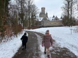 Due bambini camminano verso un castello storico innevato in Valle d’Aosta
