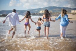 Famiglia che corre insieme sulla spiaggia al mare durante una giornata di sole