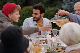 Famiglia riunita a tavola all'aperto durante un pasto conviviale