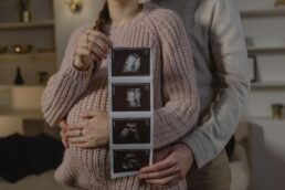 Coppia abbracciata con gravidanza, la donna mostra le ecografie del bambino in arrivo