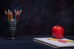 Matite colorate, quaderno e mela rappresentano simbolicamente la scuola in ospedale