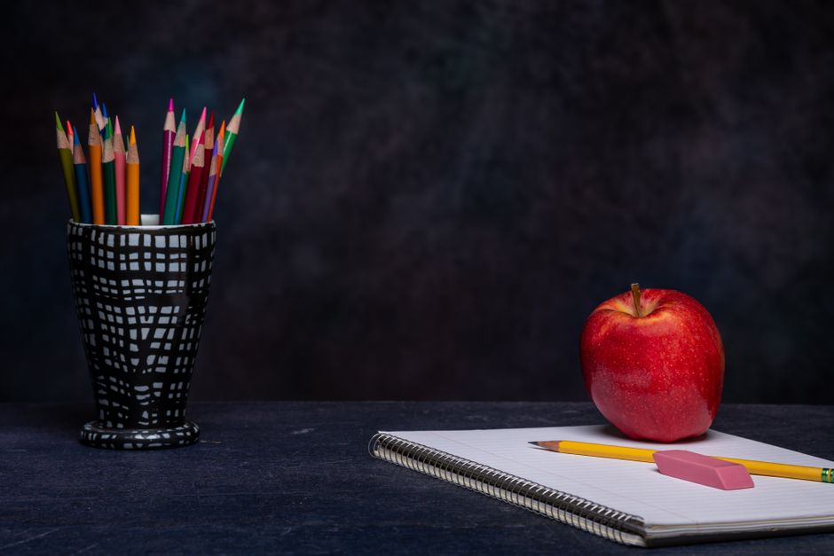 Matite colorate, quaderno e mela rappresentano simbolicamente la scuola in ospedale
