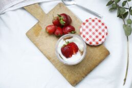 Barattolo di yogurt con fragole fresche e tagliere di legno, foto simbolica di alimentazione e fermentati
