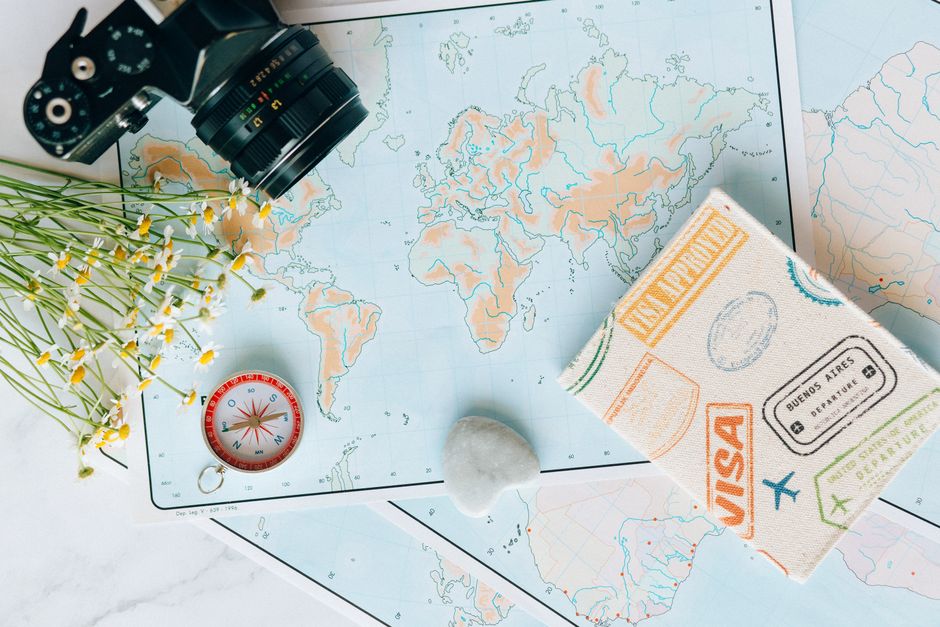 Dettaglio di mappa con macchina fotografica, bussola e passaporto, simboli di viaggio e pianificazione vacanze
