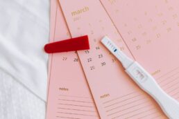 Pregnancy test and pink calendar representing fertility tracking