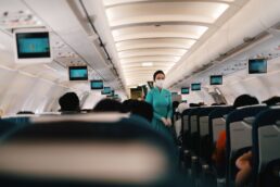 Assistente di volo in cabina durante un volo con passeggeri seduti