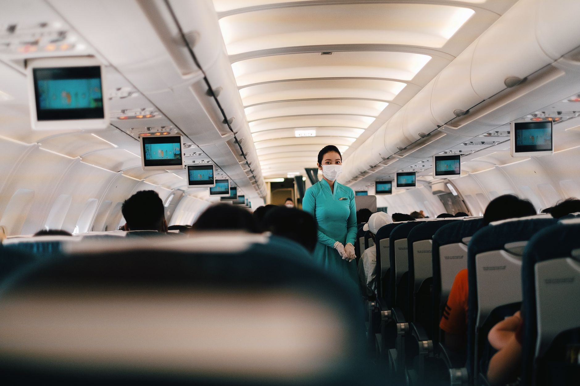 Assistente di volo in cabina durante un volo con passeggeri seduti
