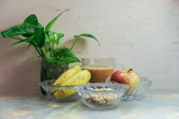 Colazione sana con frutta, cereali e bevanda in vetro su tavolo chiaro
