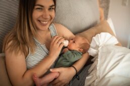 Donna che nutre un neonato con il biberon, a casa in un ambiente familiare