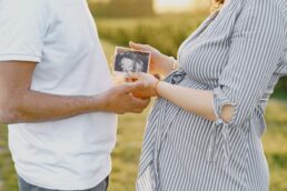 Donna incinta che mostra un'ecografia tenuta in mano da lei e da un uomo in ambiente esterno
