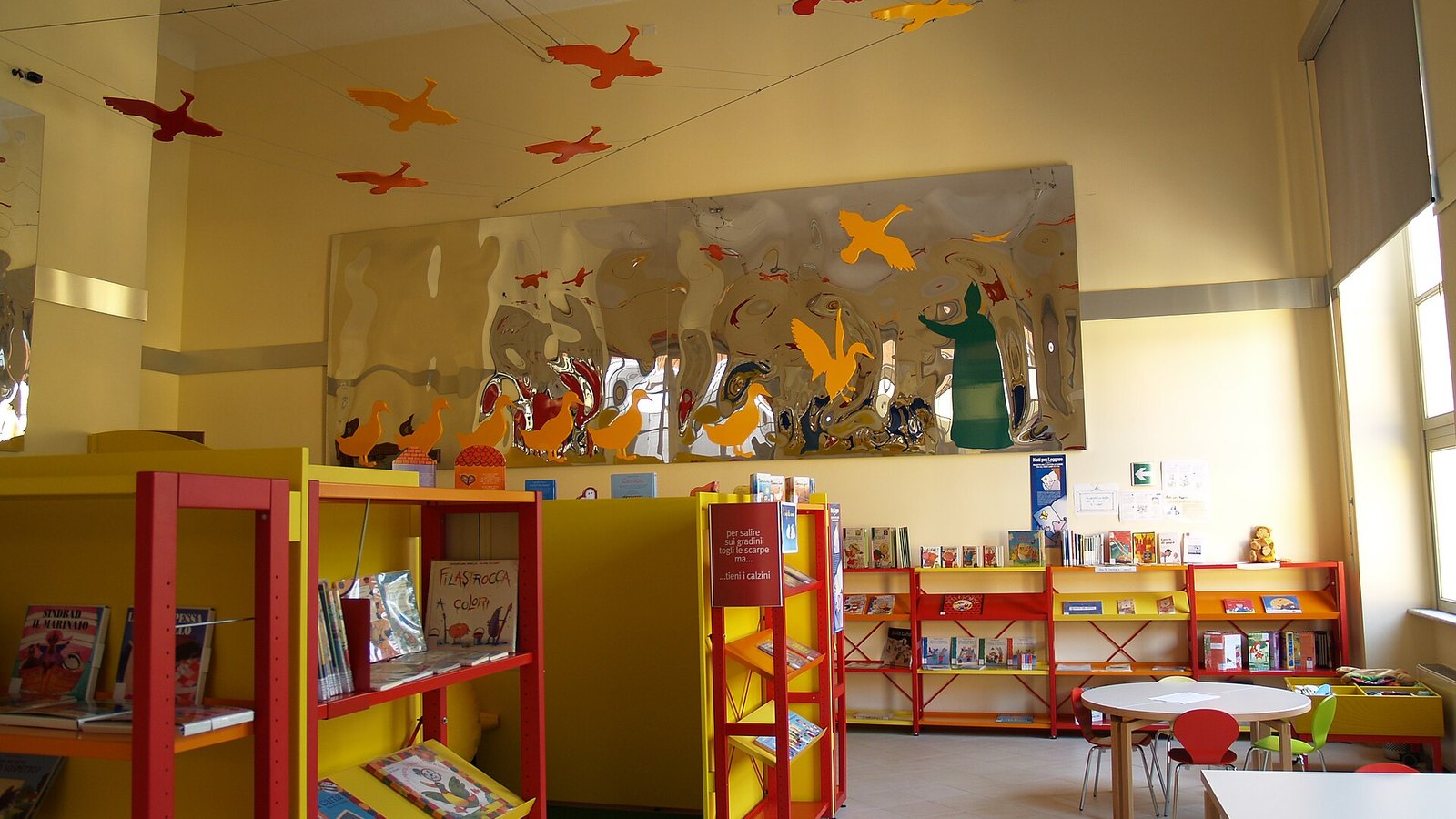 Sala di lettura per bambini con scaffali colorati pieni di libri illustrati