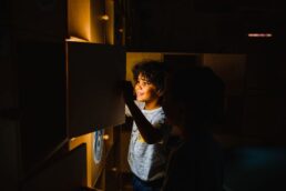 Bambino in museo interattivo con giochi e attività al chiuso in luce soffusa