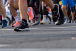 Primo piano delle scarpe da corsa di persone che corrono su strada in un evento di corsa