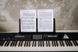 Tastiera elettronica con spartiti musicali appoggiati, simbolo di musica e apprendimento