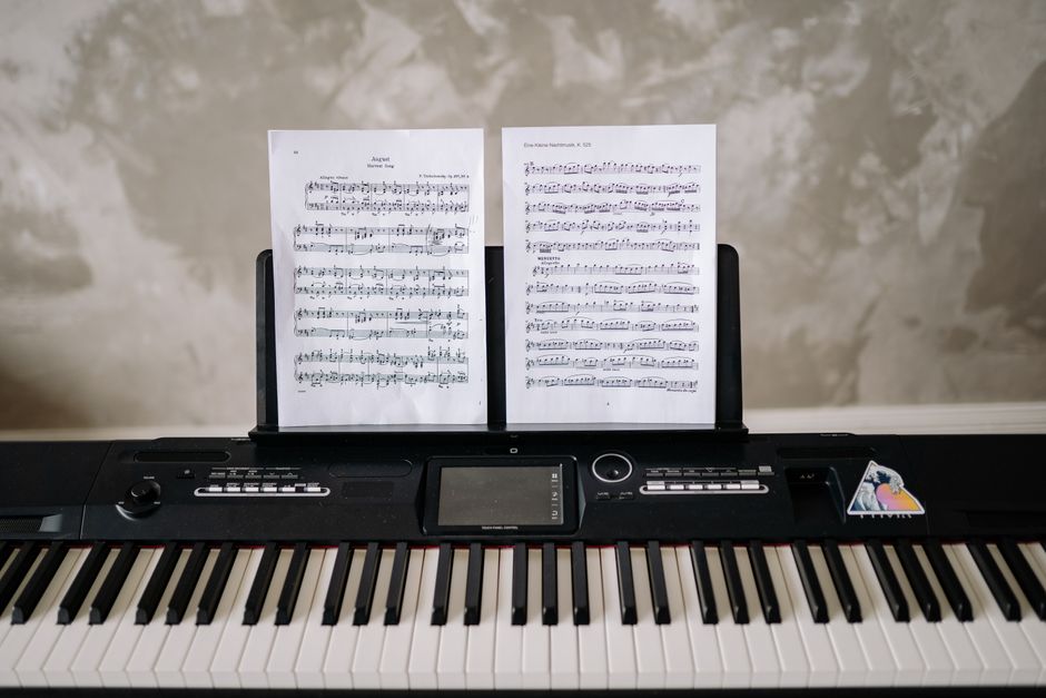 Tastiera elettronica con spartiti musicali appoggiati, simbolo di musica e apprendimento