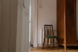 Sedia vuota in una stanza sobria con pareti chiare e pavimento in legno
