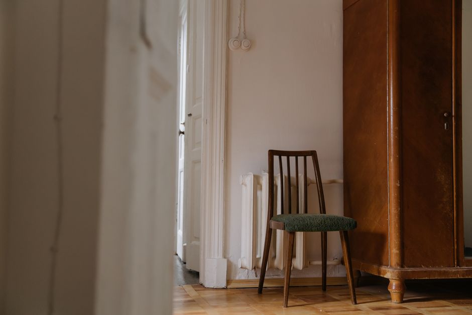 Sedia vuota in una stanza sobria con pareti chiare e pavimento in legno