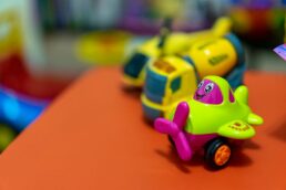Giochi di plastica colorati su un tavolo arancione, in primo piano un aeroplano giocattolo colorato