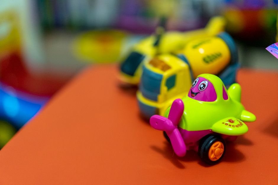 Giochi di plastica colorati su un tavolo arancione, in primo piano un aeroplano giocattolo colorato