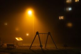 Parco giochi vuoto e poco illuminato di sera, atmosfera riflessiva e sobria