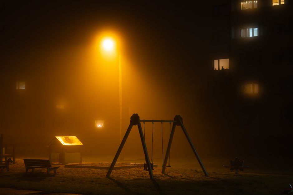 Parco giochi vuoto e poco illuminato di sera, atmosfera riflessiva e sobria