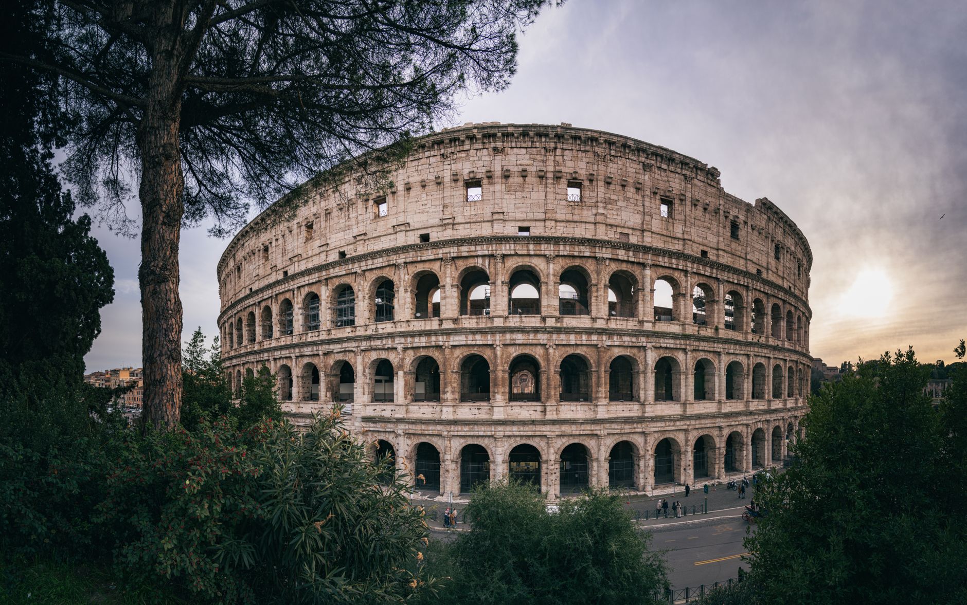 Veduta orizzontale del Colosseo a Roma con vegetazione e cielo al tramonto