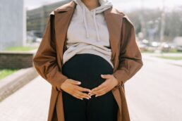 Donna incinta che tiene le mani sulla pancia all'aperto in città